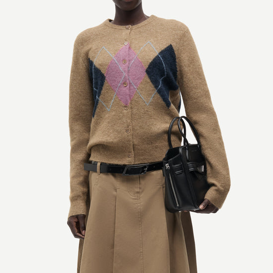 woman wearing brown pink and blue argyle cardigan on white background