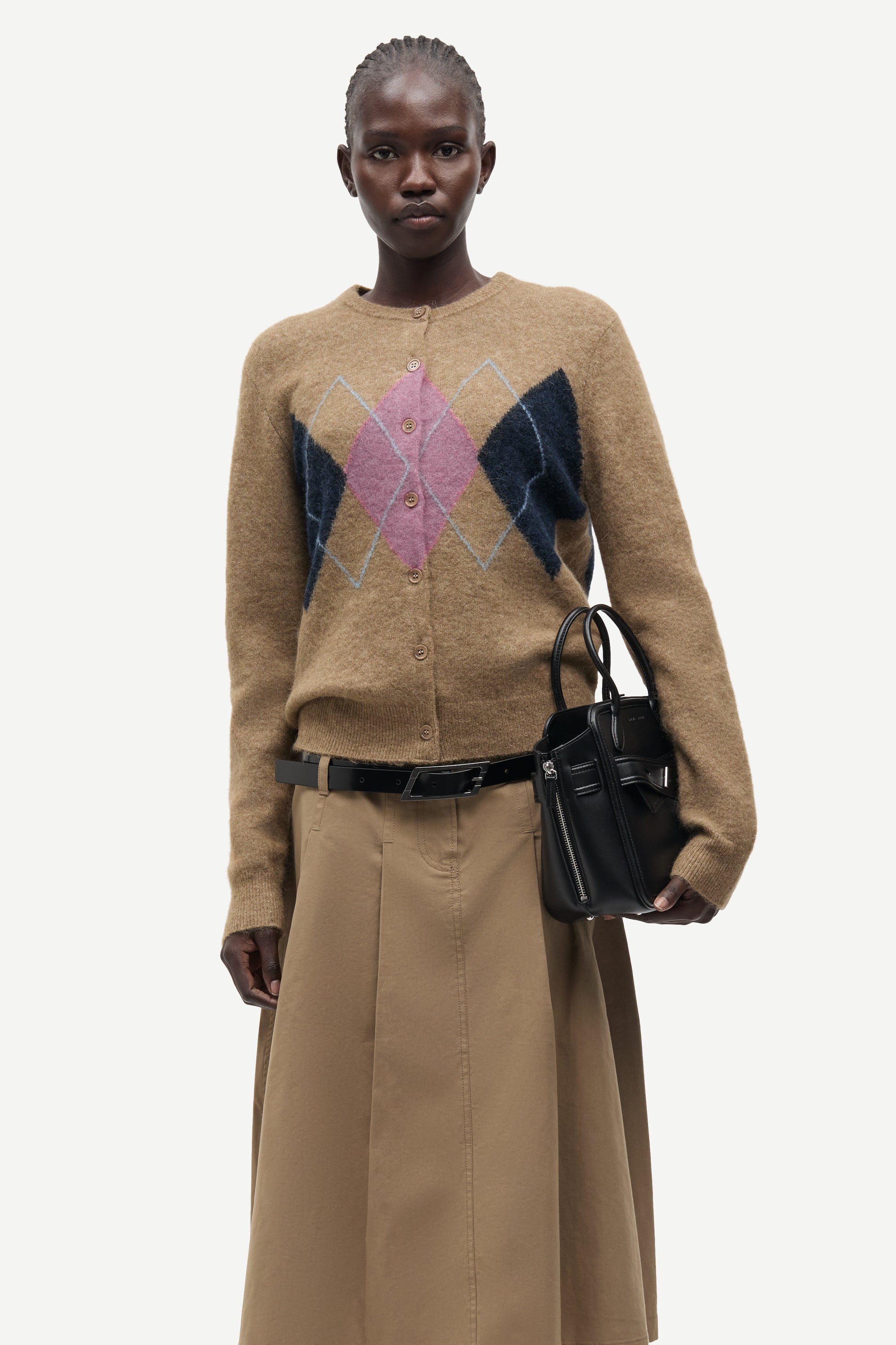 woman wearing brown pink and blue argyle cardigan on white background