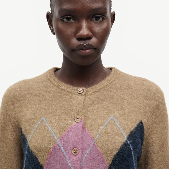 woman wearing brown pink and blue argyle cardigan on white background close up 