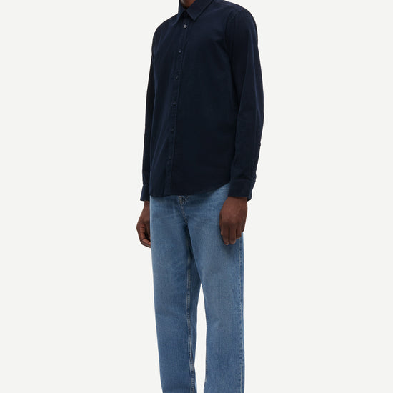 Man wearing a dark blue shirt and light blue jeans on a white background