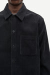 A black long-sleeve quarter-zip pullover sweater hanging on a black hanger against a plain off-white wall. The zipper pull features a small gold-tone monogram logo.