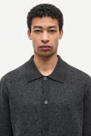 A man wearing a dark gray textured knit polo shirt with a buttoned front, shown from the chest up against a plain light background.