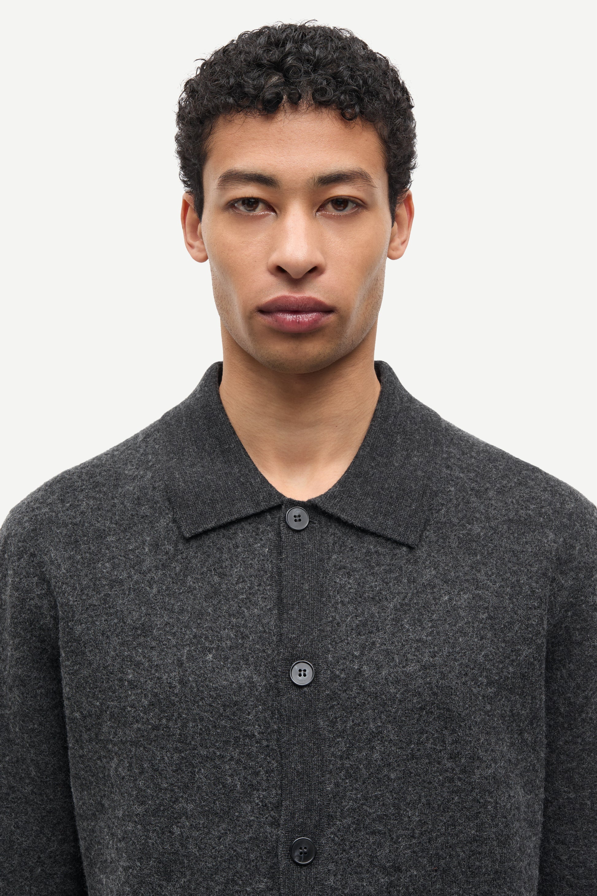 A man wearing a dark gray textured knit polo shirt with a buttoned front, shown from the chest up against a plain light background.