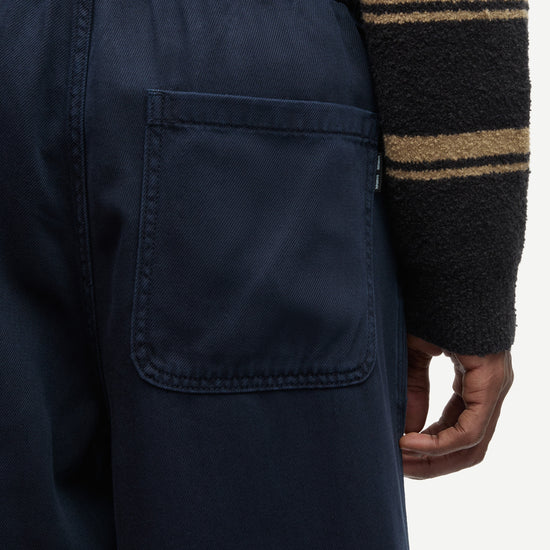 Close-up of a person wearing dark navy pants with a back pocket and a black fleece sweater featuring tan stripes.