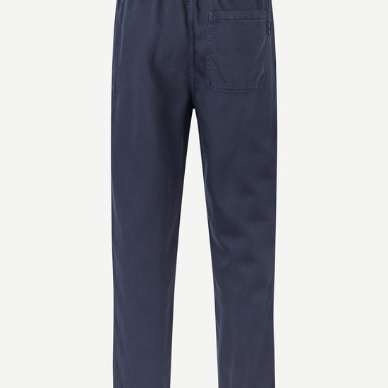 A pair of navy blue trousers shown from the back, featuring an elastic waistband and a single back pocket, displayed on a clean white background.