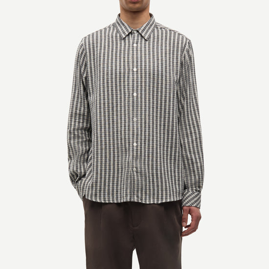 Man wearing a checkered shirt and dark pants on a white background