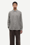 Man wearing a checkered shirt and dark pants on a white background