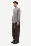Man wearing a checkered shirt and brown pants on a white background