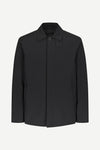 A black long-sleeve utility jacket with a pointed collar and a single button closure, displayed on a clean, light gray background.