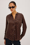 Woman wearing a brown polka dot shirt against a plain background