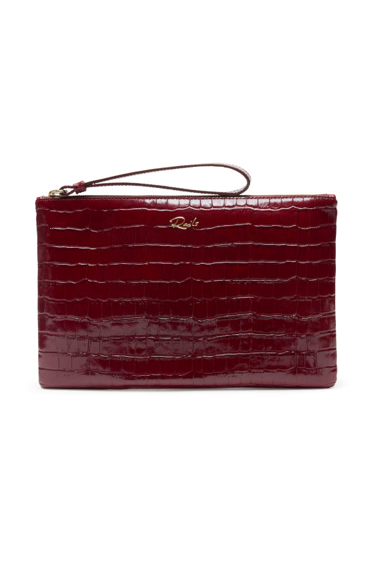 A deep burgundy crocodile-embossed leather clutch with a wristlet strap and a small gold-tone logo on the front, set against a plain white background.