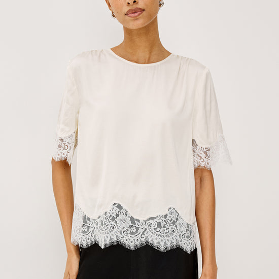 Woman wearing an ivory lace top with black trousers