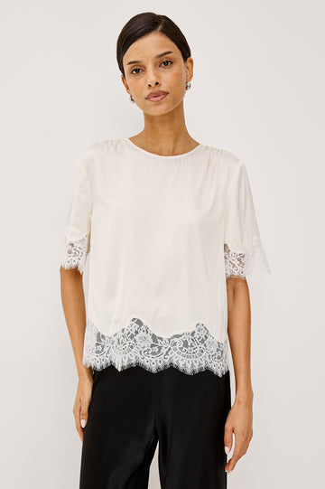 Woman wearing an ivory lace top with black trousers