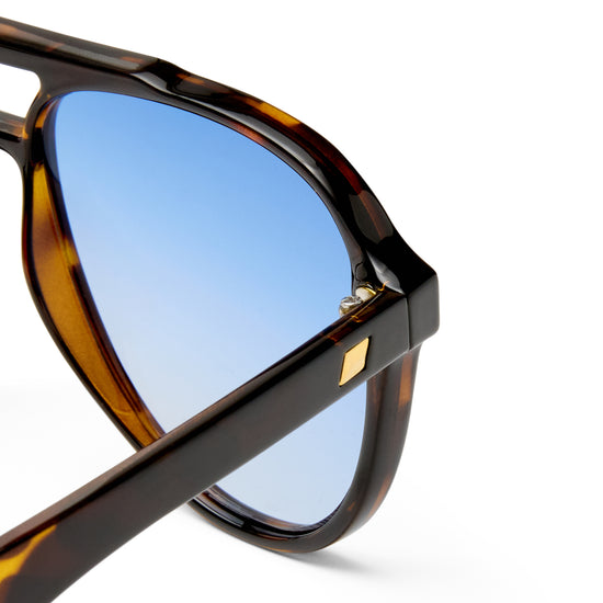 Sunglasses with tortoiseshell frame and blue lenses on a white background