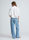 Person wearing a white shirt and light blue jeans on a plain background