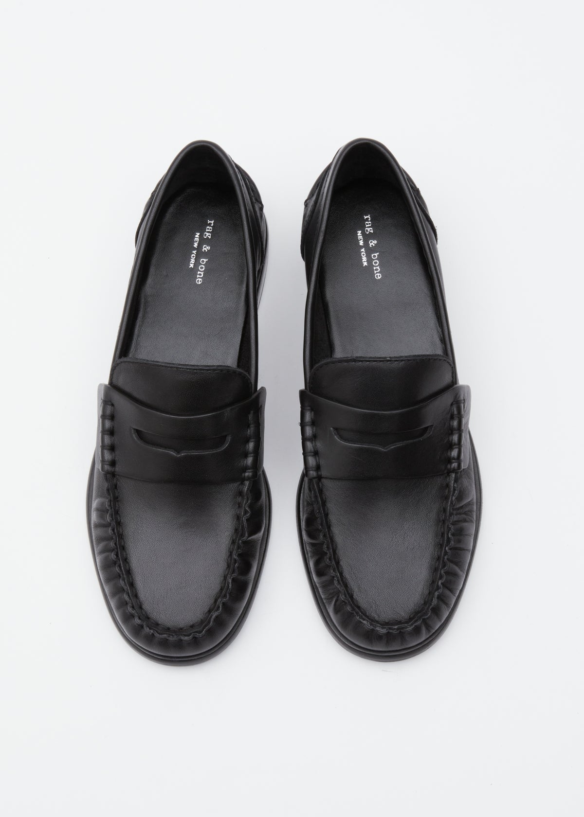A pair of black leather penny loafers with braided detailing around the sole, photographed from a top-down perspective on a clean white background.