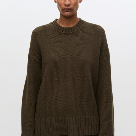 Woman wearing brown sweatshirt and black jeans