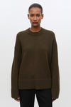 Woman wearing brown sweatshirt and black jeans