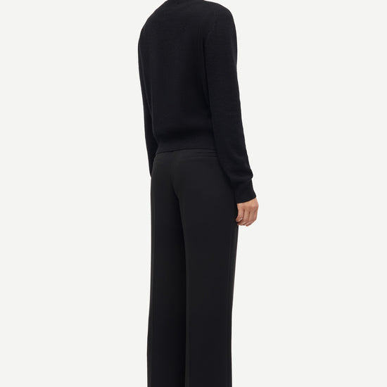 Person wearing a black sweater and pants on a white background from Samsoe Samsoe