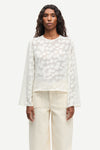 Woman wearing a cream polka dot blouse and cream pants on a white background from Samsoe Samsoe