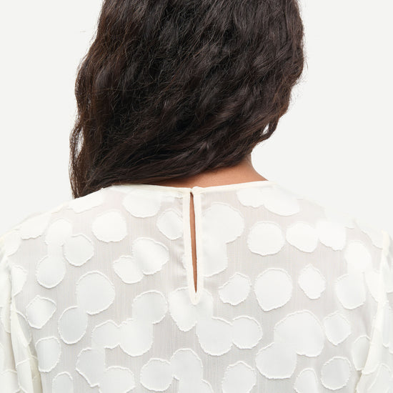 Rear view of button fastening on cream top