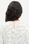 Rear view of button fastening on cream top