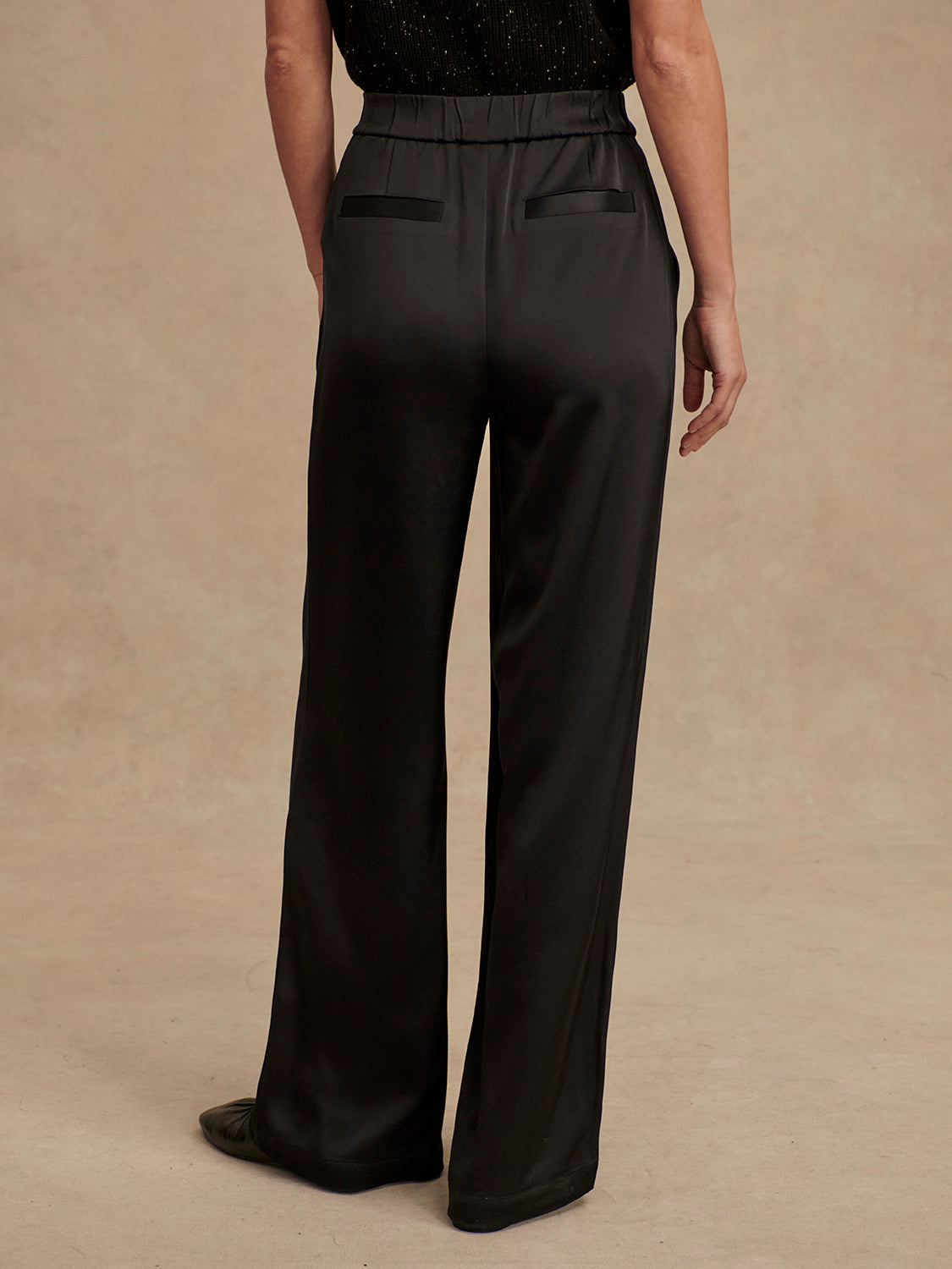 wide leg black viscose trousers with pleated front and side pockets rear view