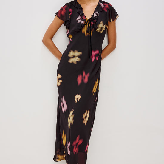 v neck long black dress with ruffled neckline and sleeves with floral blurred print model shot