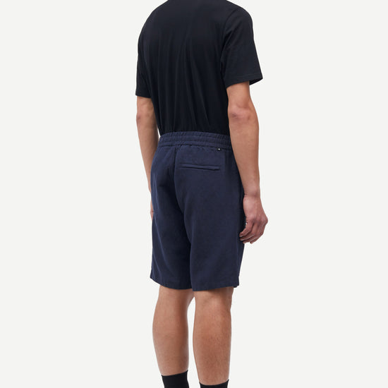 Person wearing navy shorts and a black t-shirt on a white background