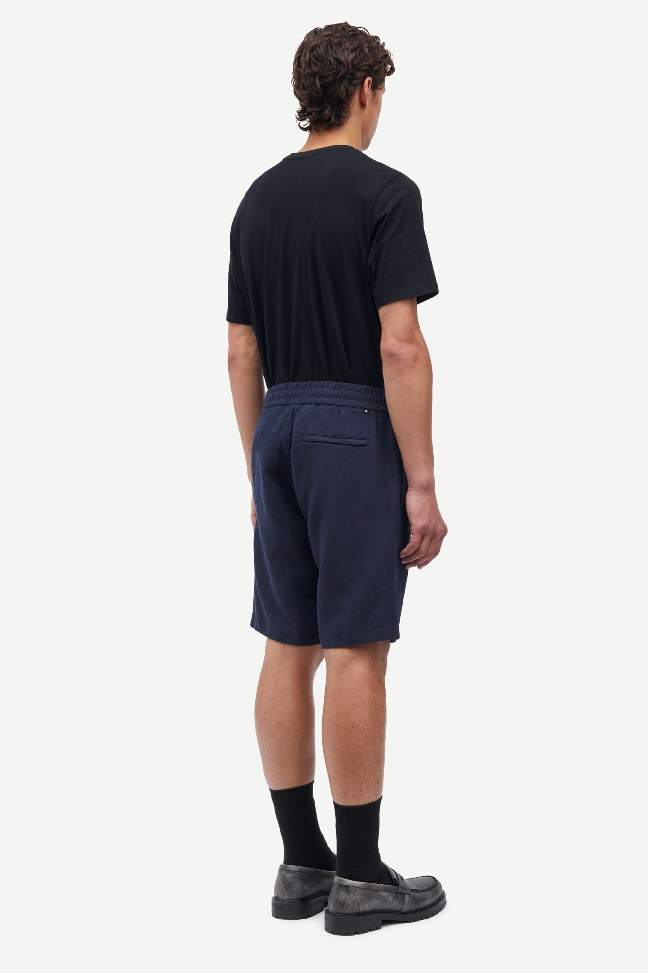 Person wearing navy shorts and a black t-shirt on a white background
