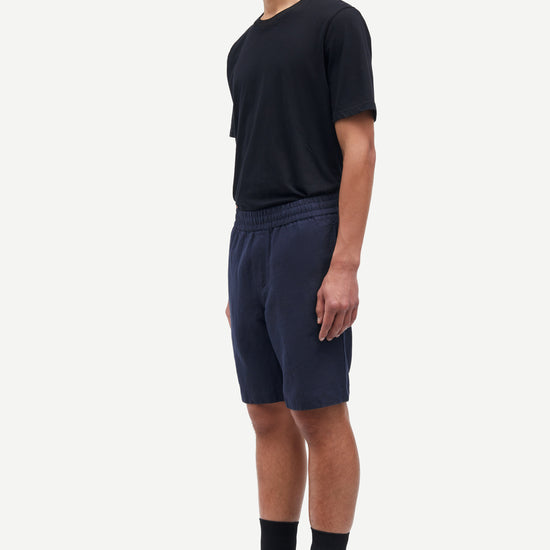 Man wearing a black t-shirt and navy shorts on a white background