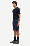 Man wearing a black t-shirt and navy shorts on a white background
