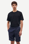 Man wearing a black t-shirt and navy shorts on a white background