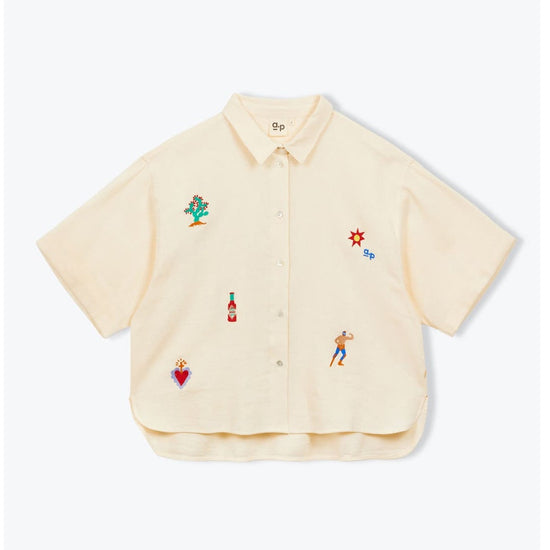 Beige shirt with colorful embroidered designs on a white background