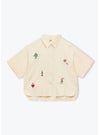 Beige shirt with colorful embroidered designs on a white background