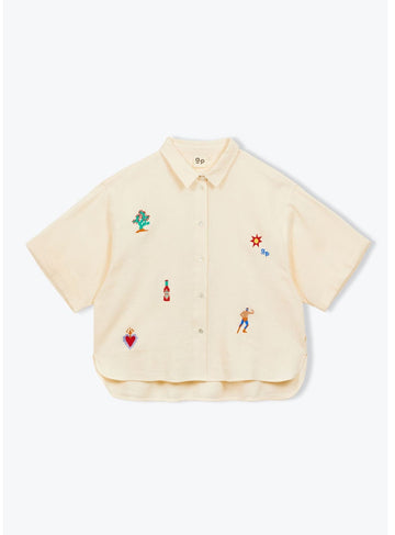 Beige shirt with colorful embroidered designs on a white background