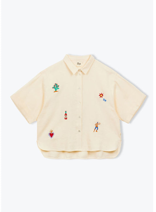 Beige shirt with colorful embroidered designs on a white background