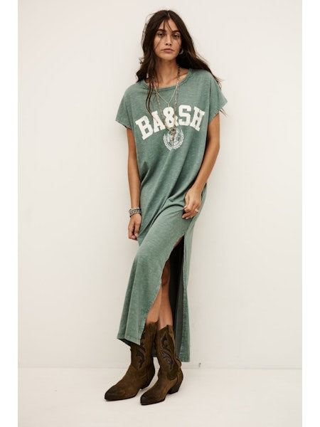 Woman wearing a green t-shirt dress with 'BA&SH' branding and brown boots on a white background