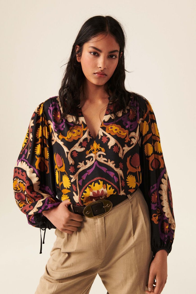 Boho inspired top with black base and bold all over print in yellows ecru and purple. Cropped balloon sleeves with tie fastening. Henley V neckline