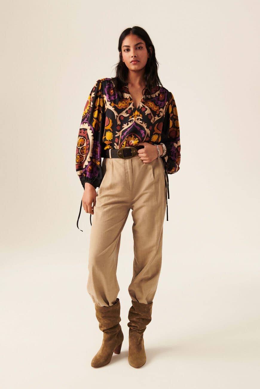 Boho inspired top with black base and bold all over print in yellows ecru and purple. Cropped balloon sleeves with tie fastening. Henley V neckline