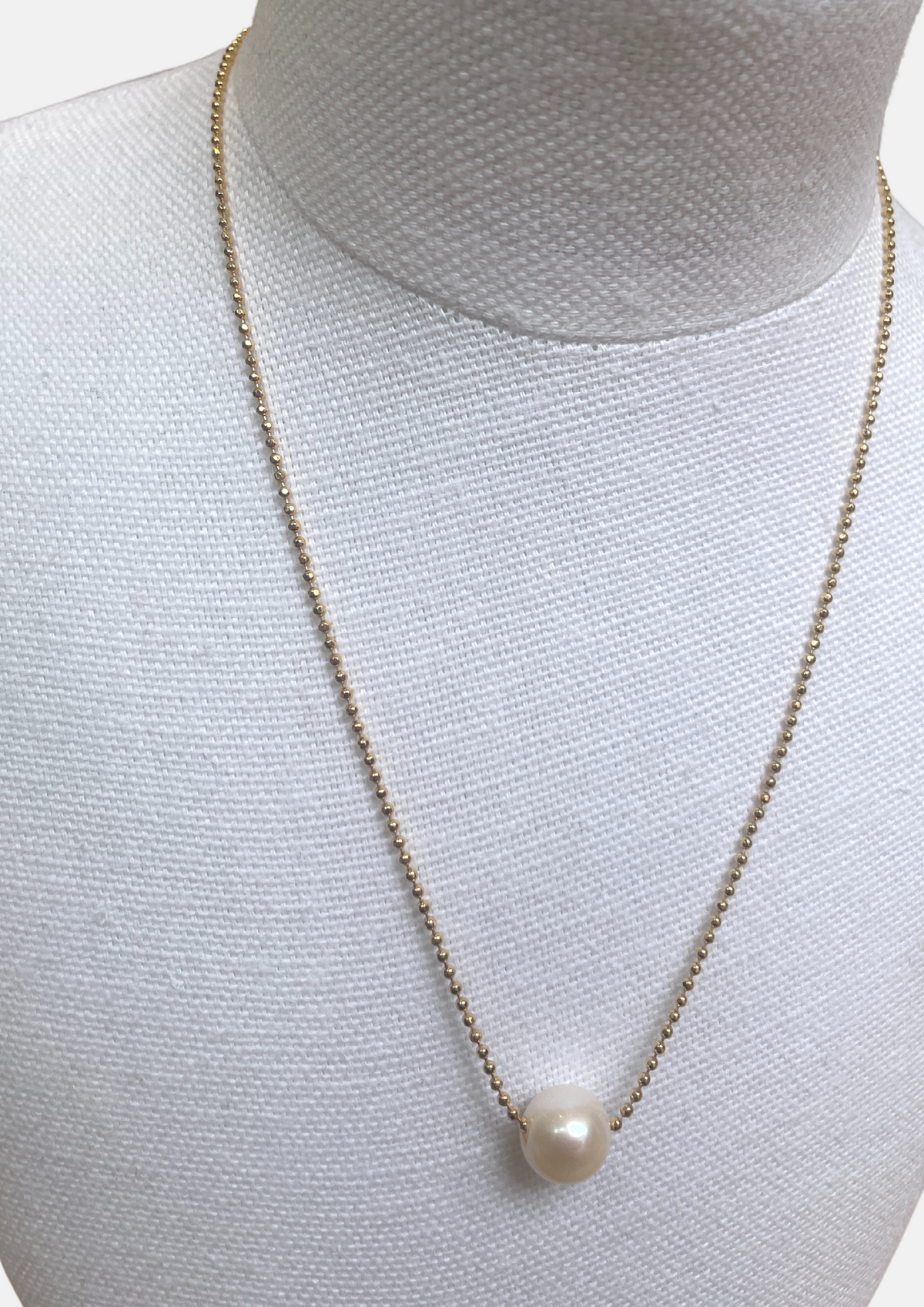 Simple pearl necklace with gold chain and singular pearl.
