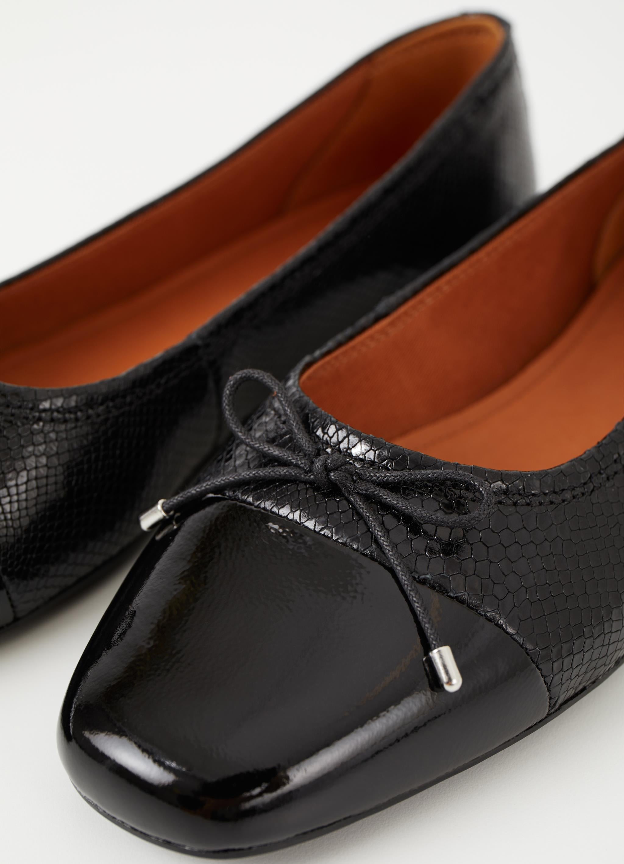 Black leather ballet pump with croc effect leather a patent toe and tie details with silver tips