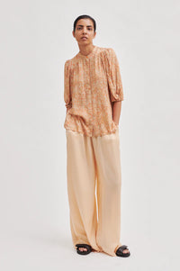 Peach and orange elbow length sleeved top with full length covered placket and elasticated cuffs