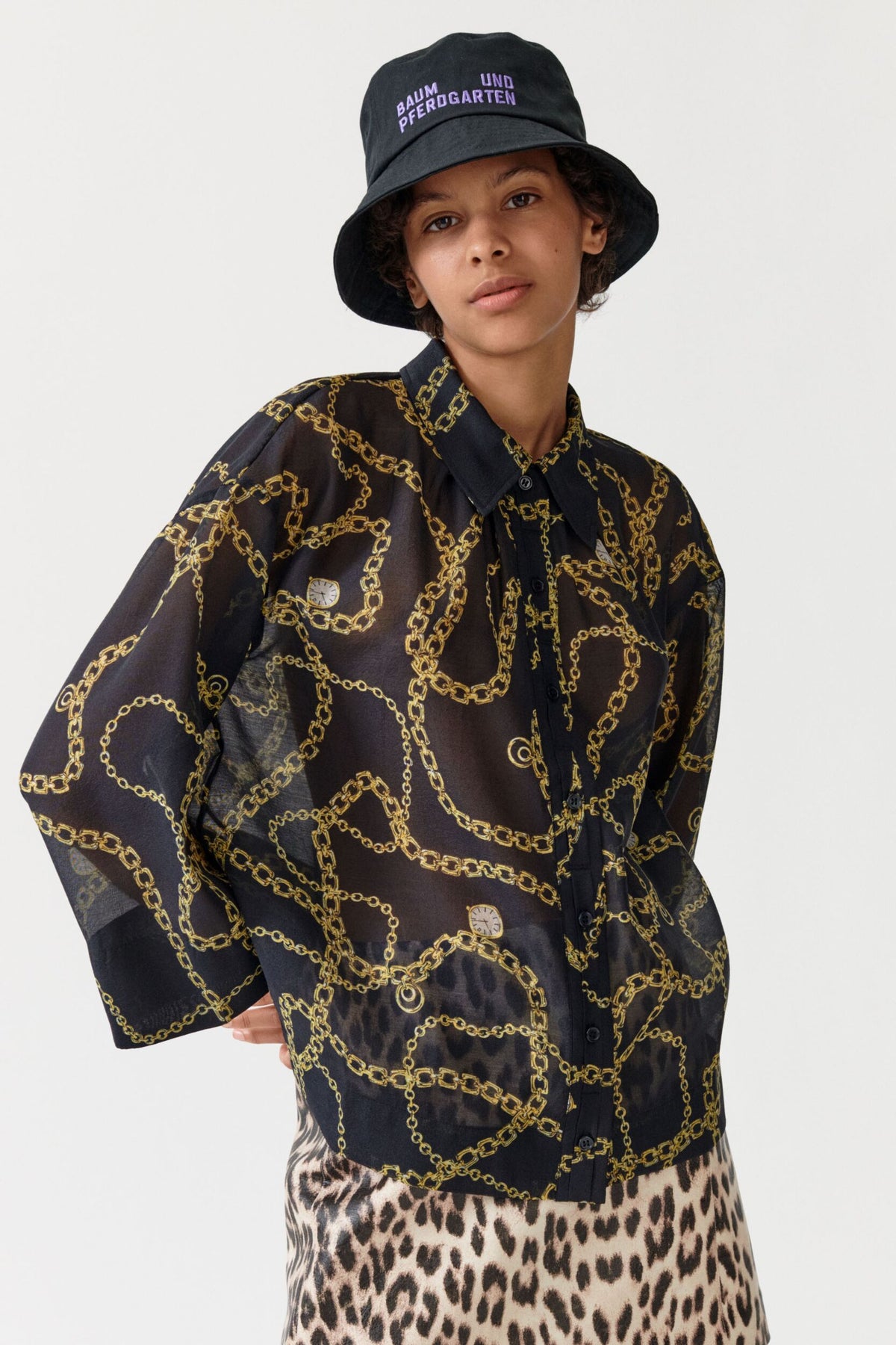 Semi sheer black shirt with classic collar and full length placket with bracelet length wide sleeves and gold chain and pocket watch all over print