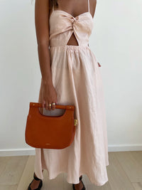 Blush pink dress with spaghetti straps knotted front midi skirt and criss cross tie detail at the back