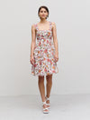 Knee length floaty summer dress with thin straps and gathering on bodice empire line in white with orange and purple floral print with purple piping detail