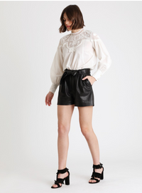 A cream blouse with lace detailing over the shoulders.