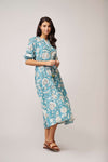 Cornflower blue dress with white leaf print button through with tie waist detail with red tassels and three quarter length sleeves