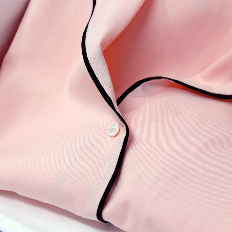 Light pink classic pyjama top and long trouser bottoms with black piping detail