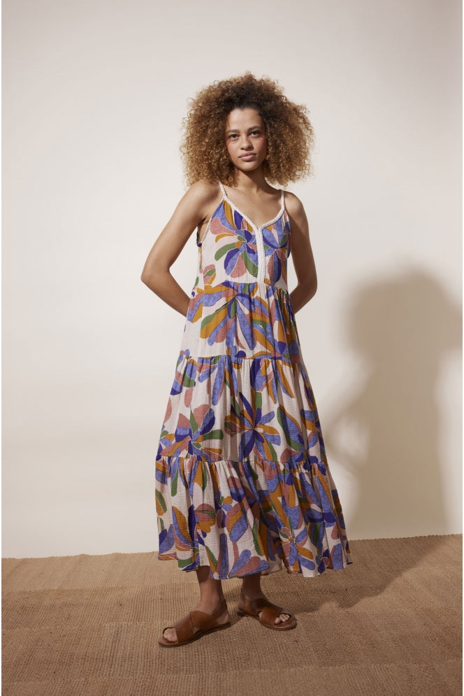 Ecru sun dress with thin straps and a bold purple green and brown floral print with triple tiered skirt